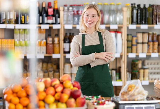 Portrait of positive female seller behind the counter of a grocery store