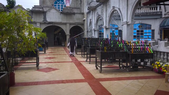 Simala Shrine - Burning Colourful Pray Candles and Passing By Monk - Catholic Church and Monastery of Holy Eucharist in Sibonga Village - Cebu Region - Philippines Landmarks - Rainy Day - LS MS 4K UHD