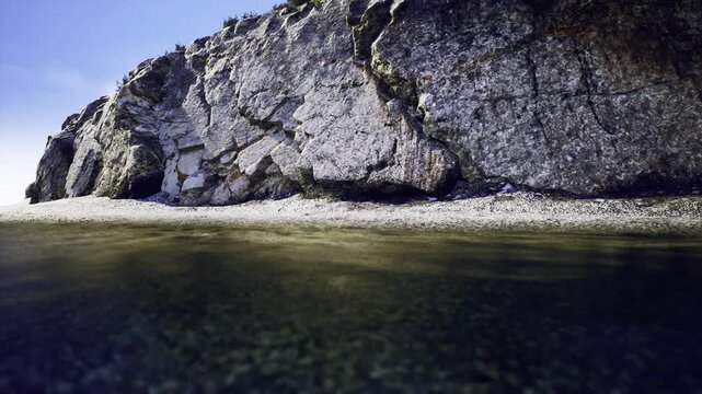 Monolithic rock wall at Los Gigantes, steep vertical face, scattered shrubs in cracks, narrow pebble fringe, dark green shallows, stark coastal solitude.