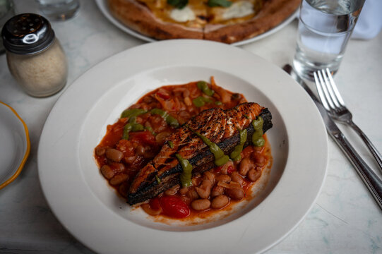 Roasted salmon dinner meal with Italian beans served in a white plate