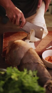 Close-up of slicing bamboo shoots on a wooden cutting board.
