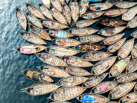 Aerial view of Sadarghat with numerous wooden boats packed closely together on the Buriganga River, featuring colorful lifebuoys and cargo in Dhaka, Dhaka Division, Bangladesh.