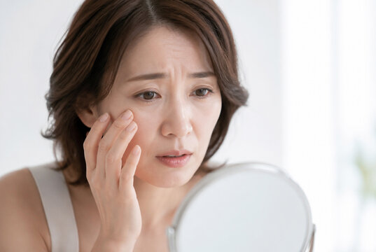鏡で顔のシワやたるみを気にする日本人女性