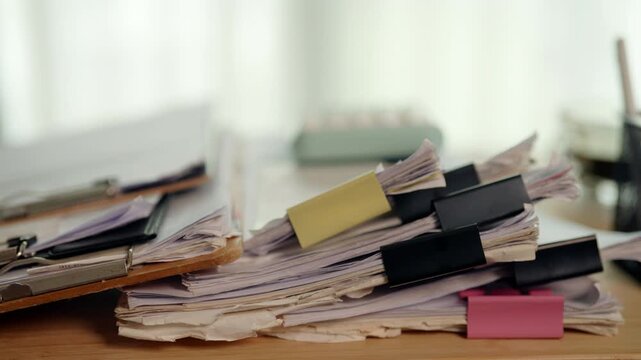 Pile of Unfinished Paperwork and Business Files on Cluttered Office Desk