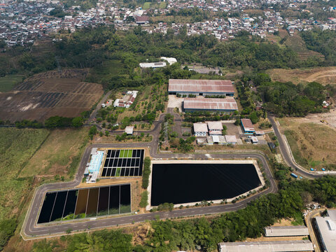 Aerial view of the leachate treatment plant and retention ponds at TPA Supit Urang, featuring industrial buildings, paved roads, and surrounding greenery in Malang, East Java, Indonesia.