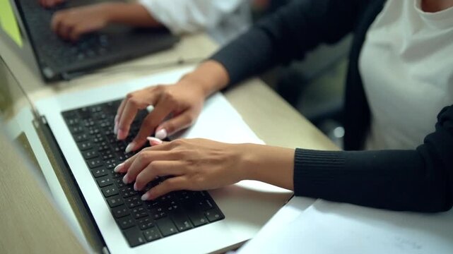 Businesswoman Typing on Laptop While Working with Colleague in Office