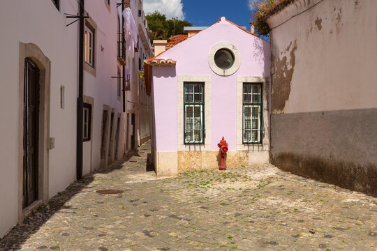 Narrow Cobblestone Courtyard with Colorful House in Alfama, Lisbon, Portugal