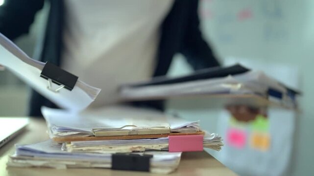 Busy Office Worker Sorting Large Stack of Business Documents and Files