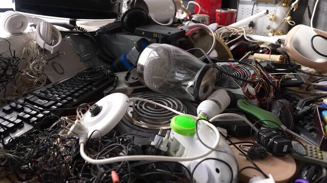 Assorted electronic devices and accessories including cables, wires, adapters, chargers, plugs, headphones, keyboard and computer mouse. Technology equipment and electronics components