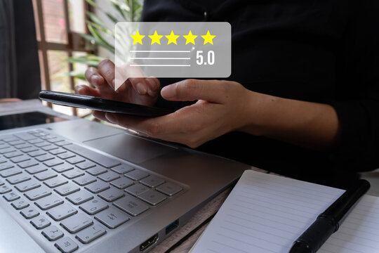 Hand holding phone with 5-star rating floating above keyboard