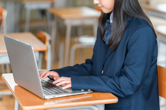 Female middle and high school students in uniform studying using computers.