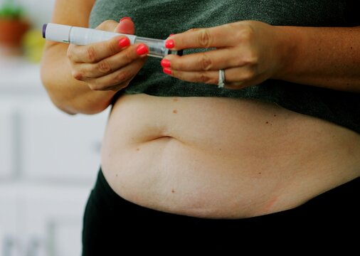 Macro shot of woman administering GLP-1 subcutaneous injection into stomach tissue for weight management, obesity, or diabetes care - food noise med