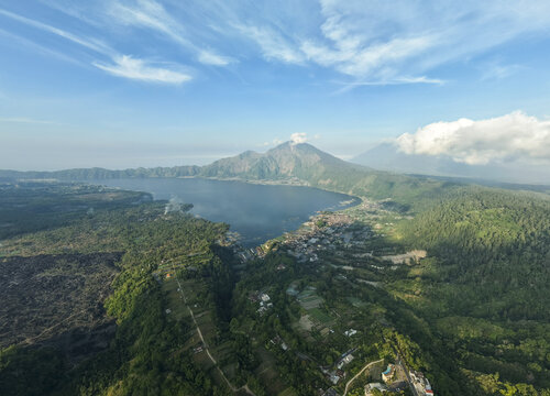 Aerial view of Mount Abang overlooking Lake Batur with lush green forests, volcanic terrain, and the village of Kintamani, Bali, Indonesia.