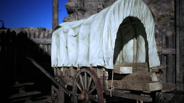 Canvas covered wagon resting on wooden wheels in open sun weathered canvas drape, spoked wheel detail, rope ties, dusty ground and distant rocky ridge,