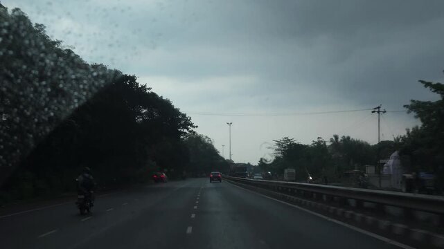 Stormy Evening Road with Traffic Under Dark Monsoon Clouds in India, Cars Driving on Wet Urban Highway, Dramatic Sky, Tropical Trees, Rainy Weather, Travel and Road Transportation Footage