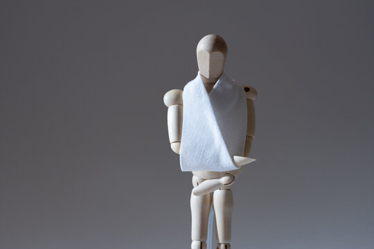 腕を怪我して三角巾をしている木の人形