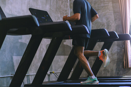 Fit young man workout jogging in machine treadmill at fitness gym. Selected focus