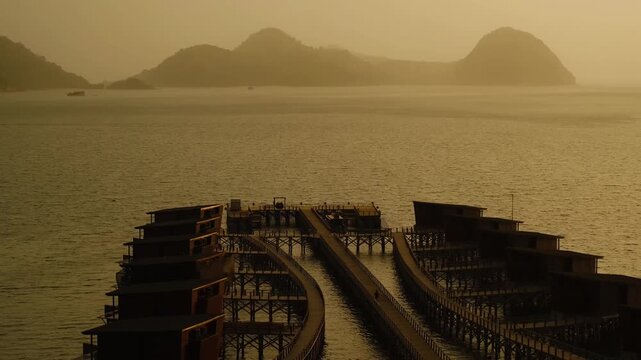 Pier with Overwater Villas Extending into the Ocean at Sunset with Islands on the Horizon, 4K 50fps