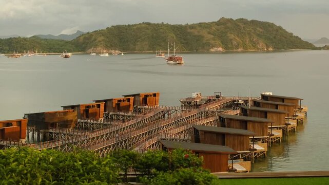 Pier with Overwater Villas Extending into the Ocean at Sunset with Islands on the Horizon, 4K 50fps
