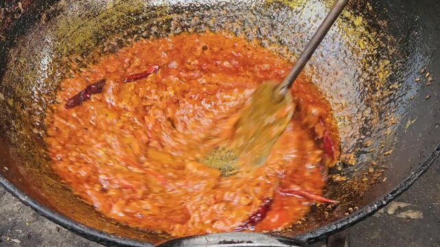Traditional Indian Cooking in Large Iron Wok, Spicy Curry Masala Being Prepared in Outdoor Kitchen, Authentic Indian Food Preparation with Oil, Tomato and Turmeric, Street Food and Cuisine