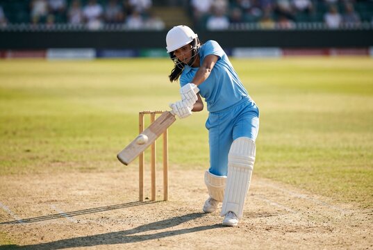 Female Cricketer Swinging Bat on Pitch During Professional Cricket Match