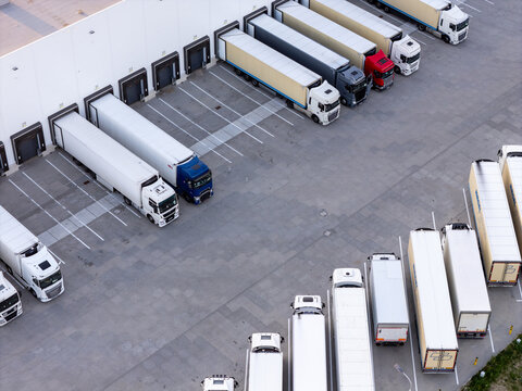 Aerial view of a logistics distribution center with multiple semi-trucks parked at loading bays for cargo loading and unloading in Gdansk, Poland.
