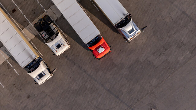Aerial view of three semi-trucks parked in a row on an asphalt lot in Gdansk, Poland.