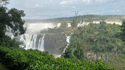 Majestic Iguazu Falls in Brazil showcasing powerful cascades surrounded by lush green rainforest under a cloudy sky © Felippe Lopes