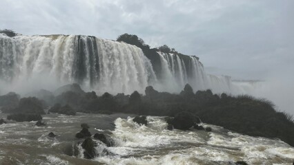 Majestic Iguazu Falls in Brazil with powerful cascades and lush green surroundings under a cloudy sky © Felippe Lopes