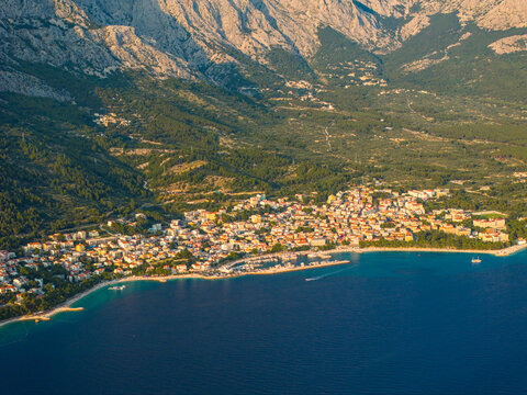 Aerial view of the coastal town of Brela, nestled between the Adriatic Sea and the Biokovo mountains, with stone houses and a small harbor in Brela, Split-Dalmatia County, Croatia.
