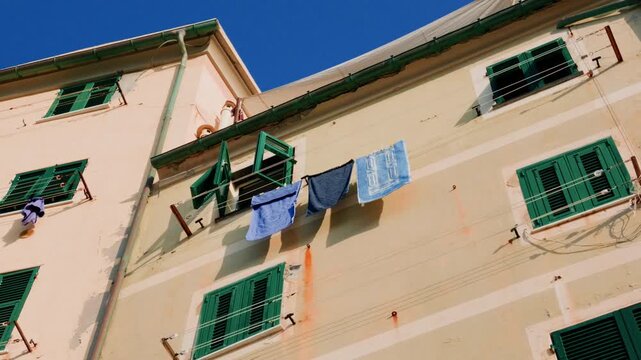 Colorful building facade with green shutters and laundry drying on clotheslines outside