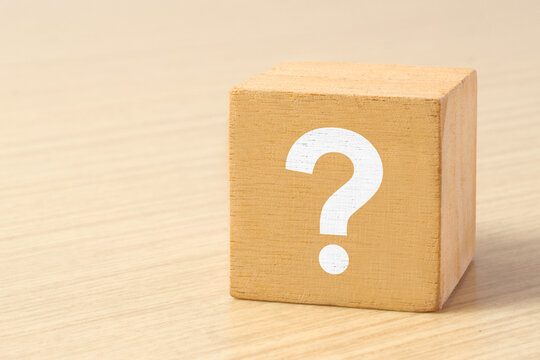 A question mark is printed on a wooden block, the concept of thinking, doubting and looking for an answer.