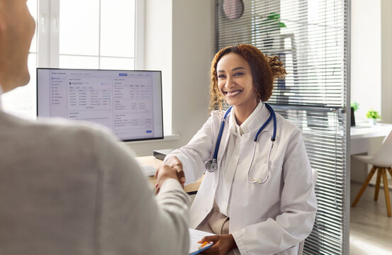 Doctor and patient handshake during healthcare consultation appointment. In a bright clinic, a doctor explains diagnosis, builds trust and offers support. Concept shows trusted patient care.
