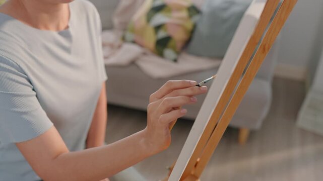 Caucasian female artist painting artwork on canvas frame at home studio. 