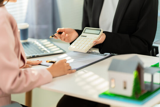 A real estate agent is presenting a modern home design to a buyer during a consultation and explaining the benefits of a home loan.