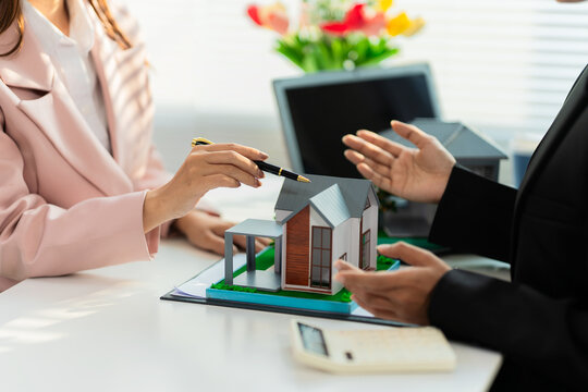 A real estate agent is presenting a modern home design to a buyer during a consultation and explaining the benefits of a home loan.