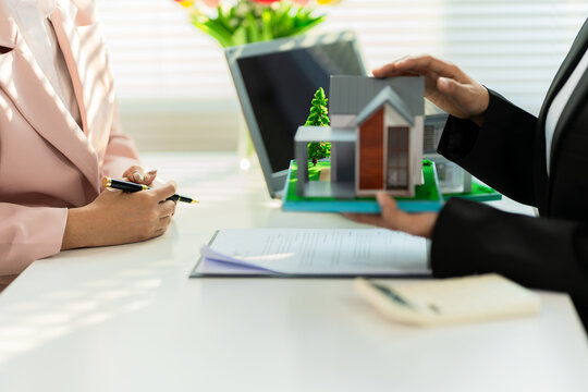 A real estate agent is presenting a modern home design to a buyer during a consultation and explaining the benefits of a home loan.