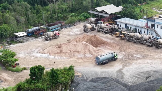 Aerial view of cement mixer trucks parked in a row and piles of raw materials for cement production