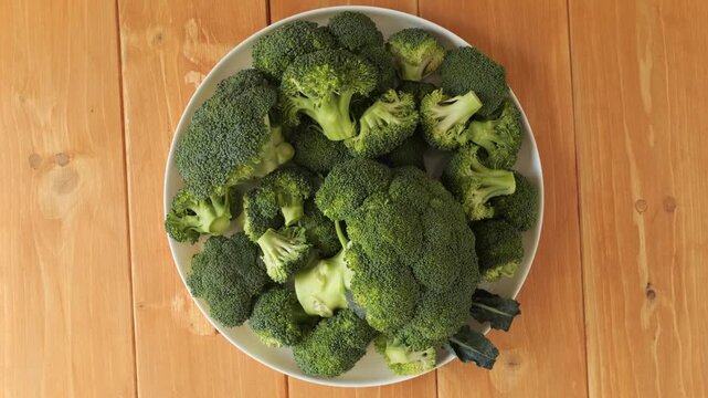 Fresh green broccoli florets rotating on a plate