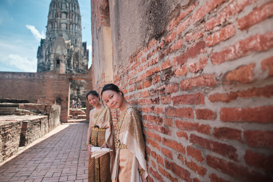 Asian family, mother and child dressed in Thai traditional outfit with cheerful smiles and looking at camera, holiday travel in Ayutthaya, Southeast Asia, ancient ruins heritage,  tourist destination.