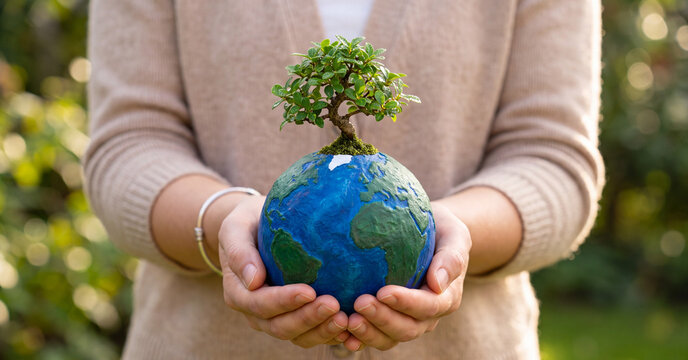 Earth globe with growing bonsai tree held in female hands representing environmental sustainability, ecological protection, nature conservation, and global climate