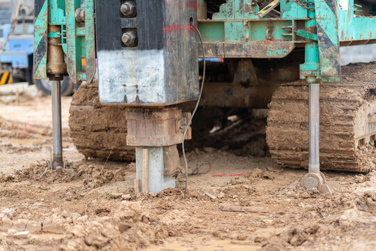 Heavy construction machinery driving a precast concrete pile into muddy soil to build strong structural foundations.