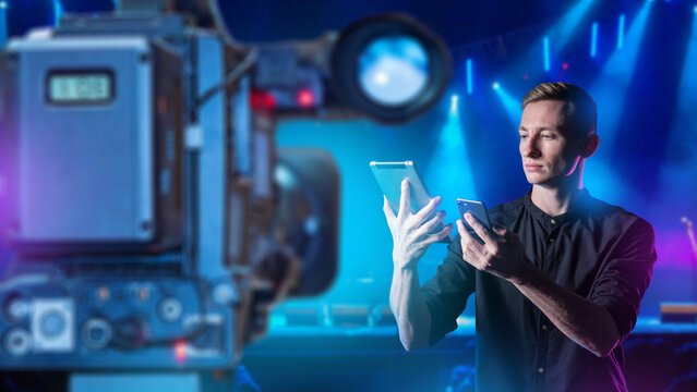 Live streaming. Content creator manages a live video broadcast with a professional camera while using a smartphone and tablet for remote production and audience control.