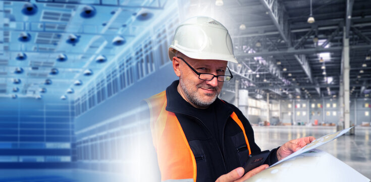 Industrial construction. Site engineer reviews project documentation inside manufacturing facility during warehouse commissioning and industrial building inspection.