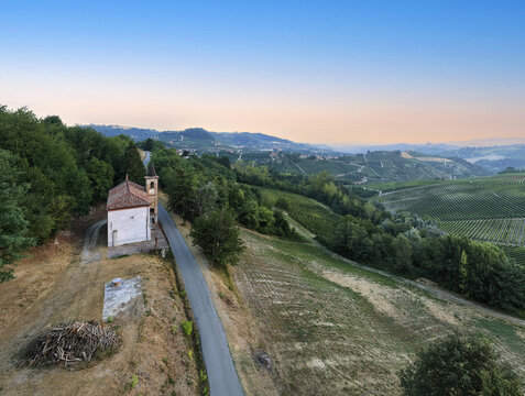 Aerial view of the Chapel of San Bernardo situated along a quiet road amidst the rolling vineyards of Monforte d'Alba, Piedmont, Italy.