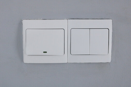 A set of three modern rectangular light switches installed on a light grey wall indoors.