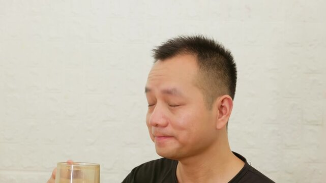 Asian man looks surprised and delighted after tasting coffee.