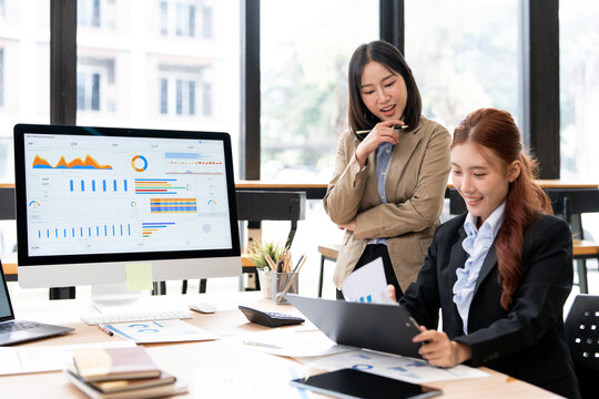 Asian Business Women Analyzing Financial Data and Charts on Computer Screen in Office
