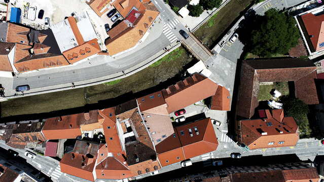 Aerial view of the historic town of Samobor, featuring traditional red-tiled rooftops, a winding stream, narrow streets, and parked cars in Samobor, Zagreb County, Croatia.