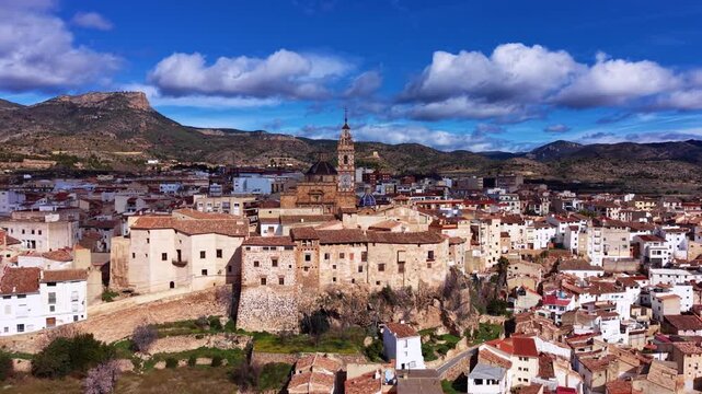 Chelva traditional Spanish village in Valencia region, Spain, featuring historic church tower, stone buildings, terracotta rooftops and mountain landscape under blue sky